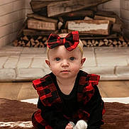 Elliana is registered to the contest to win money with this photo: baby, child, plaid, dress, headband, bow, fireplace, firewood, rug, floor, indoors, person, cute, sitting, portrait, blue_eyes, clothing, infant, home, cozy