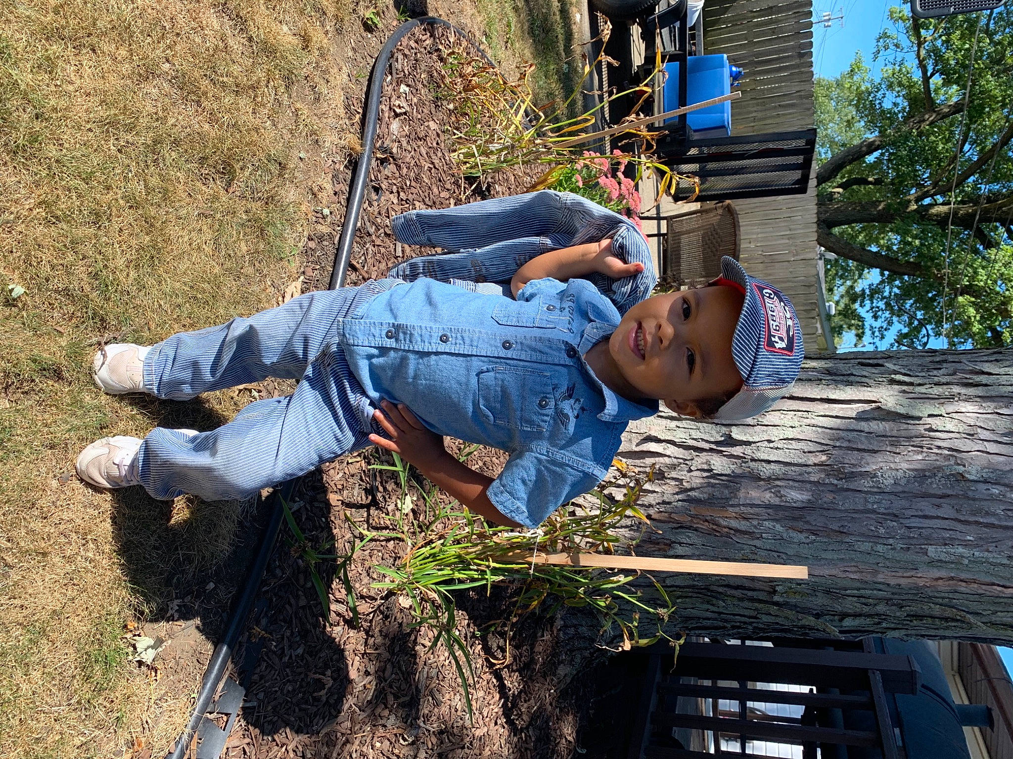 Demari is registered to the contest to win money with this photo: denim, electric_blue, fun, grass, happy, hat, headwear, jeans, leisure, luggage_and_bags, people_in_nature, person, plant, sitting, sneakers, soil, t_shirt, tree, wood