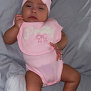 Eliana is registered to the contest to win money with this photo: baby, infant, pink, headband, socks, bib, sleepy, bed, blanket, clothing, person, cute, child, indoor, portrait, relaxing, adorable, soft, bow, skin