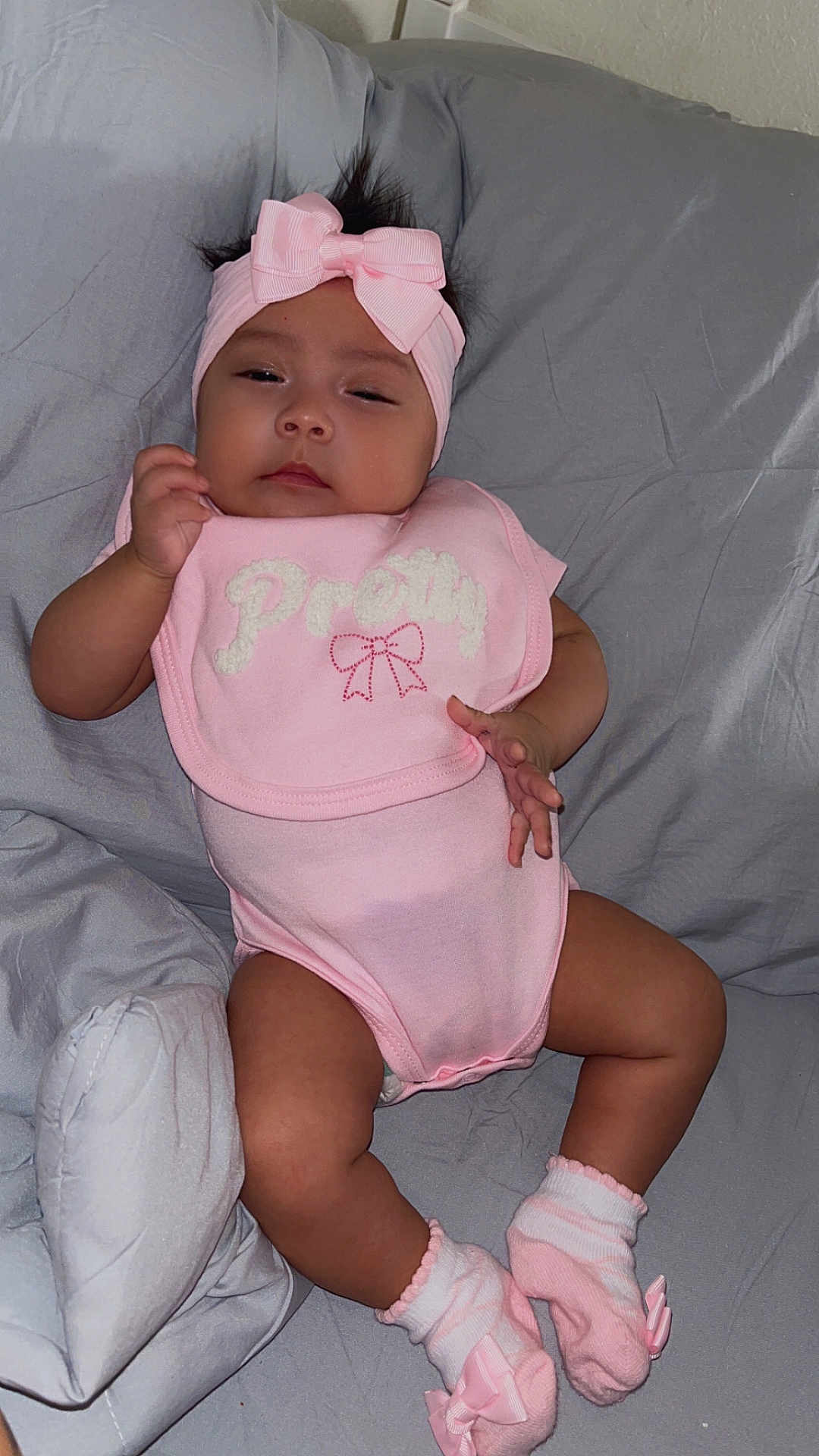 Eliana is registered to the contest to win money with this photo: baby, infant, pink, headband, socks, bib, sleepy, bed, blanket, clothing, person, cute, child, indoor, portrait, relaxing, adorable, soft, bow, skin