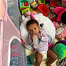 Harmony joined the competition — help win amazing prizes! baby, bottle, unicorn_pillow, toy, playpen, diaper, child, indoor, floor, colorful, stuffed_animal, pink, green, purple, red, smiling, curly_hair, cute, relaxed, infant
