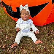 Harmony is registered to the contest to win money with this photo: baby, child, infant, halloween, pumpkin, inflatable, grass, outdoor, costume, white_clothing, headband, smile, cute, fall, leaves, festive, holiday, seasonal, fun, portrait