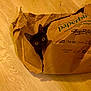 cat, black_cat, paper_bag, floor, wooden_floor, curious, pet, animal, indoor, crumpled_paper, wide_eyes, playful, cute, domestic_cat, feline, looking_up, ears, head, mischievous, peeking
