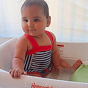 Aelfwynn joined the competition — help win amazing prizes! baby, child, bathtub, water, swimsuit, striped_clothing, red_straps, pony_tail, infant, sitting, curious, water_droplets, plastic_tub, indoor, cute, young_child, playtime, relaxed, skin, face