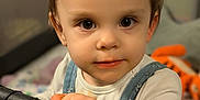 Savannah is registered to the contest to win money with this photo: toddler, child, face, hands, denim_overalls, white_shirt, playpen, indoor, curious, big_eyes, messy_face, baby, young_child, portrait, looking_at_camera, closeup, skin, hair, expression, toy