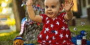 Savannah is registered to the contest to win money with this photo: arms_up, blue_blanket, celebration, child, cute, decorations, grass, happy, nature, outdoor, patriotic, portrait, red_dress, smiling, stars, stuffed_animal, sunlight, toddler, toy, tree_trunk