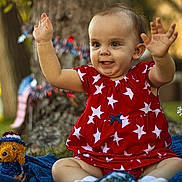 Savannah joined the competition — help win amazing prizes! baby, child, red_dress, stars, outdoor, grass, tree, blue_blanket, toy, decorations, happy, smiling, cute, sitting, festive, patriotic, sparkle, celebration, hands_up, portrait