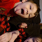 Luca is registered to the contest to win money with this photo: black_clothing, casual, child, couch, cozy, expression, face, fun, happy, home, indoor, kids, pajamas, person, plaid, playful, red_clothing, sitting, smiling, tongue_out