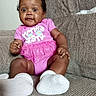 baby, infant, child, pink_clothing, tutu, white_socks, couch, furniture, indoor, portrait, smiling, cute, seated, person, face, happy, young_child, home, cozy, curious