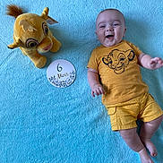Jean a rejoint le concours — aidez-le/la à gagner de superbes lots ! baby, infant, smiling, yellow_clothing, plush_toy, simba, blue_blanket, milestone_card, lying_down, cute, happy, child, soft_texture, portrait, six_months, toddler, toy, clothing, baby_boy, indoor