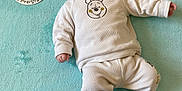 Jean a rejoint le concours — aidez-le/la à gagner de superbes lots ! baby, infant, child, tongue_out, white_clothing, bear_design, blanket, turquoise, soft_texture, lying_down, card, age_marker, cute, playful, smiling, sock, cozy, indoors, portrait, person