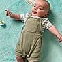 baby, infant, child, tongue_out, overalls, striped_shirt, pacifier, blanket, soft_texture, age_marker, cute, playful, lying_down, smiling, indoors, skin, head, arms, legs, button