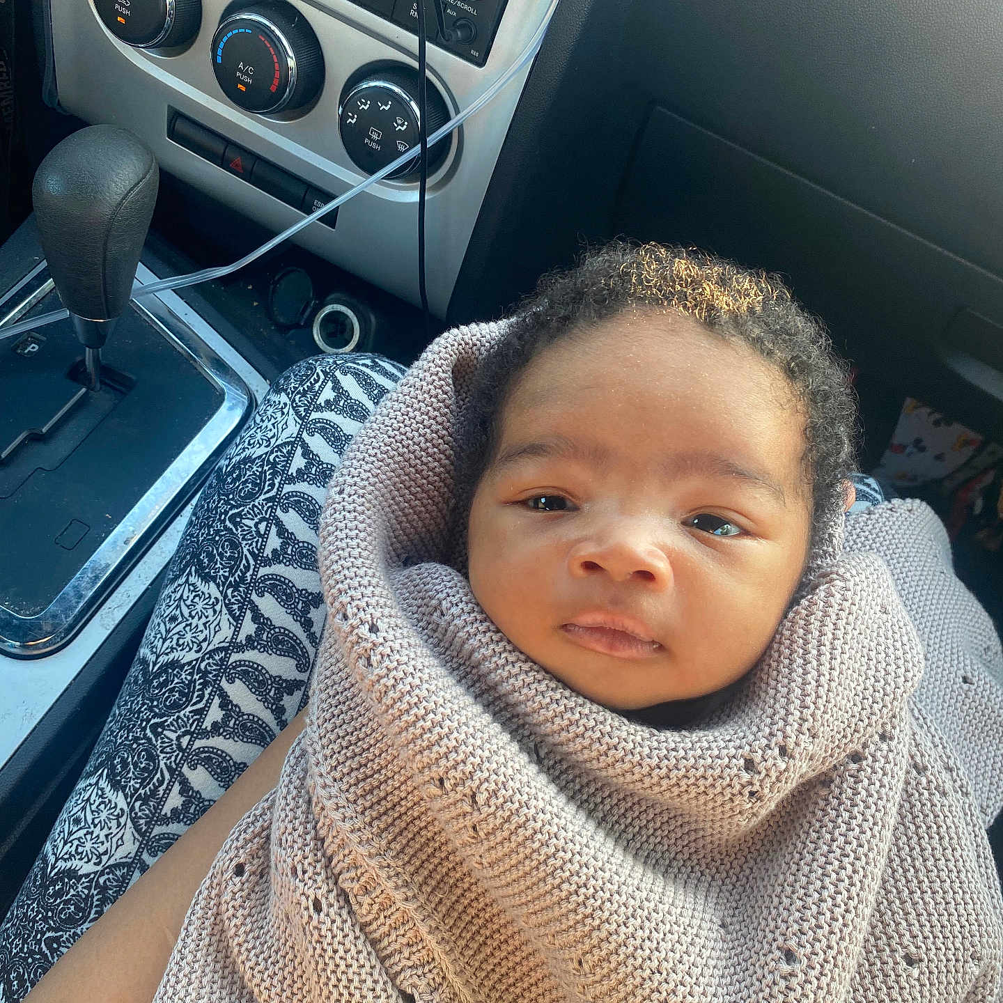 Legend Johnson is registered to the contest to win money with this photo: baby, blanket, calm, car, car_interior, car_seat, child, close_up, cozy, dashboard, face, gear_shift, indoor, infant, knitted, looking_at_camera, portrait, stereo, vehicle, wrapped
