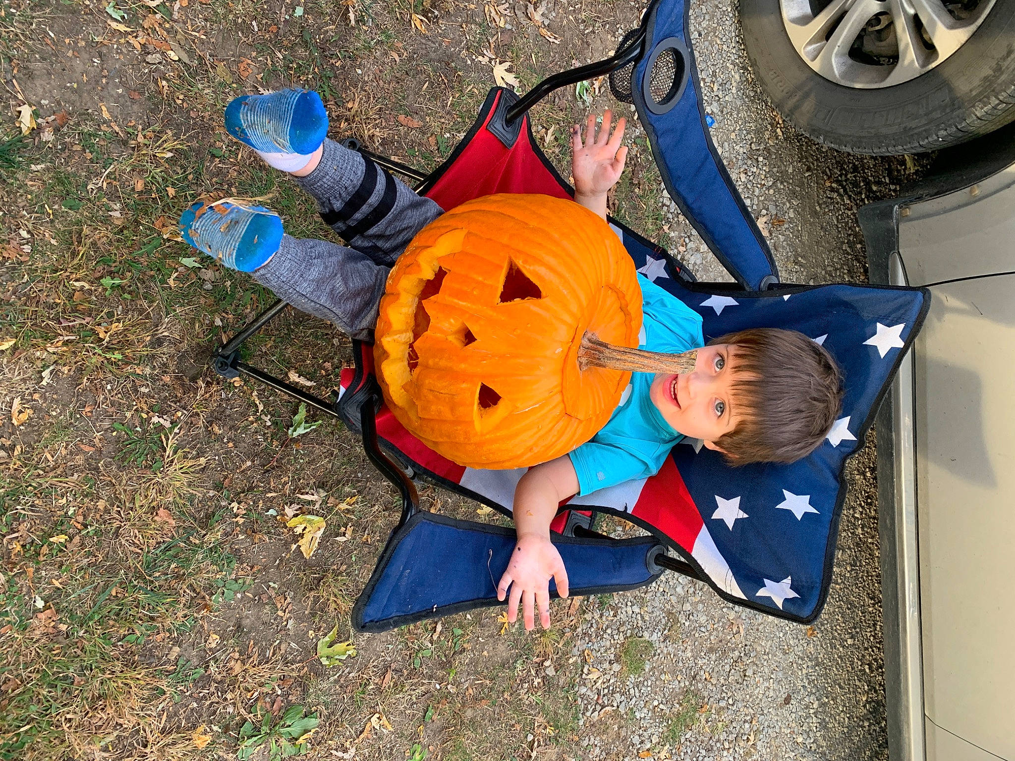 Daxton is registered to the contest to win money with this photo: asphalt, automotive_tire, automotive_wheel_system, car, child, electric_blue, fender, fun, grass, hat, leisure, motor_vehicle, person, rim, smile, tire, tire_care, toddler, toy, vehicle