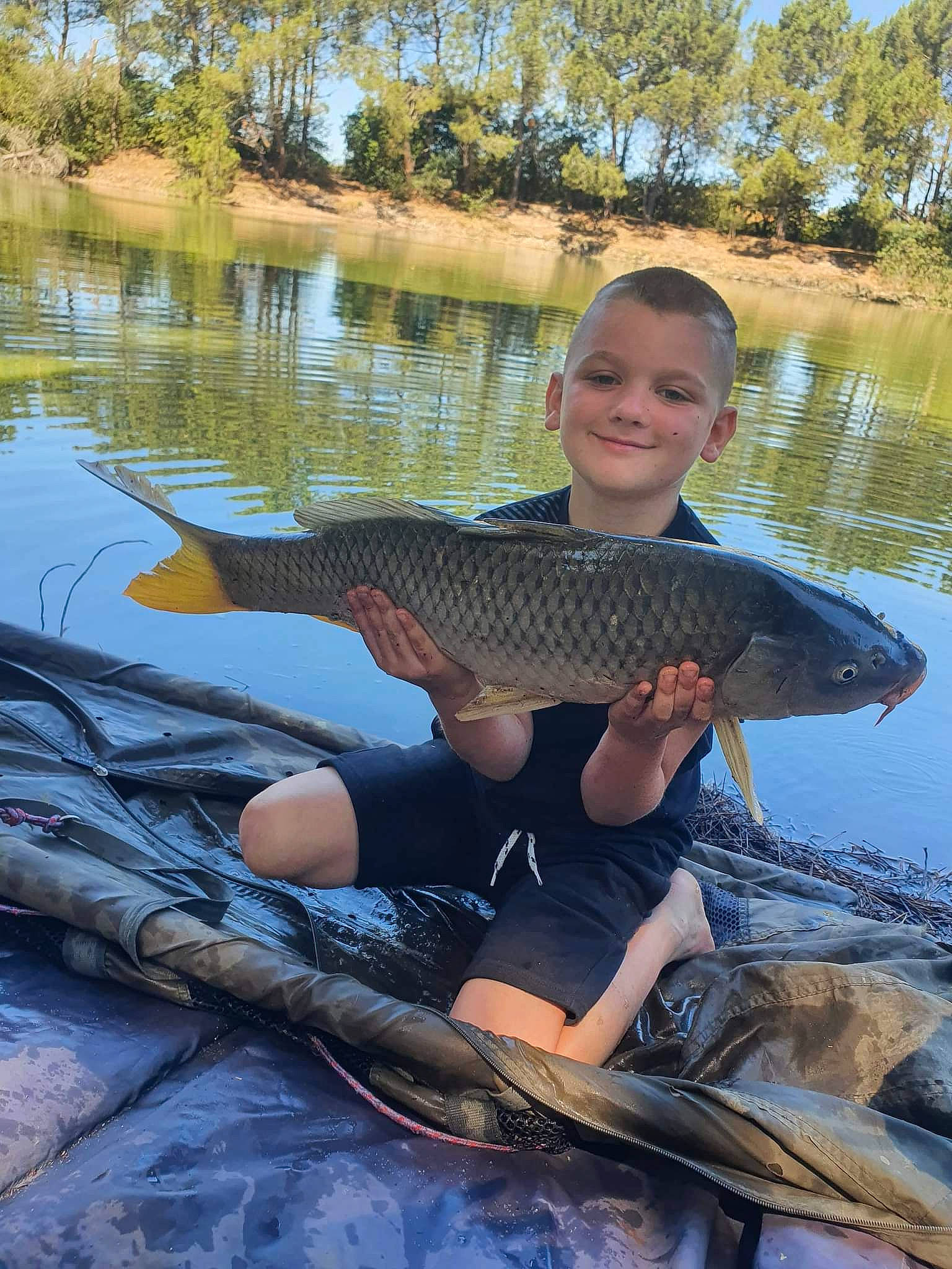 Kelyan participe au concours pour gagner de l'argent avec cette photo : boat, boats_and_boating_equipment_and_supplies, fin, fish, fisherman, fishing, joy, lake, leisure, outdoor_recreation, person, plant, ray_finned_fish, recreation, recreational_fishing, reservoir, sky, smile, tree, water