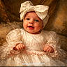 baby, child, smiling, dress, bow, headwear, portrait, cute, happy, infant, face, clothing, fabric, lace, pearl, sitting, warm_tones, background, elegant, portrait_photography