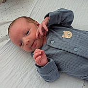 Jacob joined the competition — help win amazing prizes! baby, infant, newborn, onesie, grey_clothing, bear_patch, blanket, white_blanket, star_pattern, lying_down, small_hands, face, head, person, cute, soft_texture, sleepwear, indoors, portrait, newborn_baby