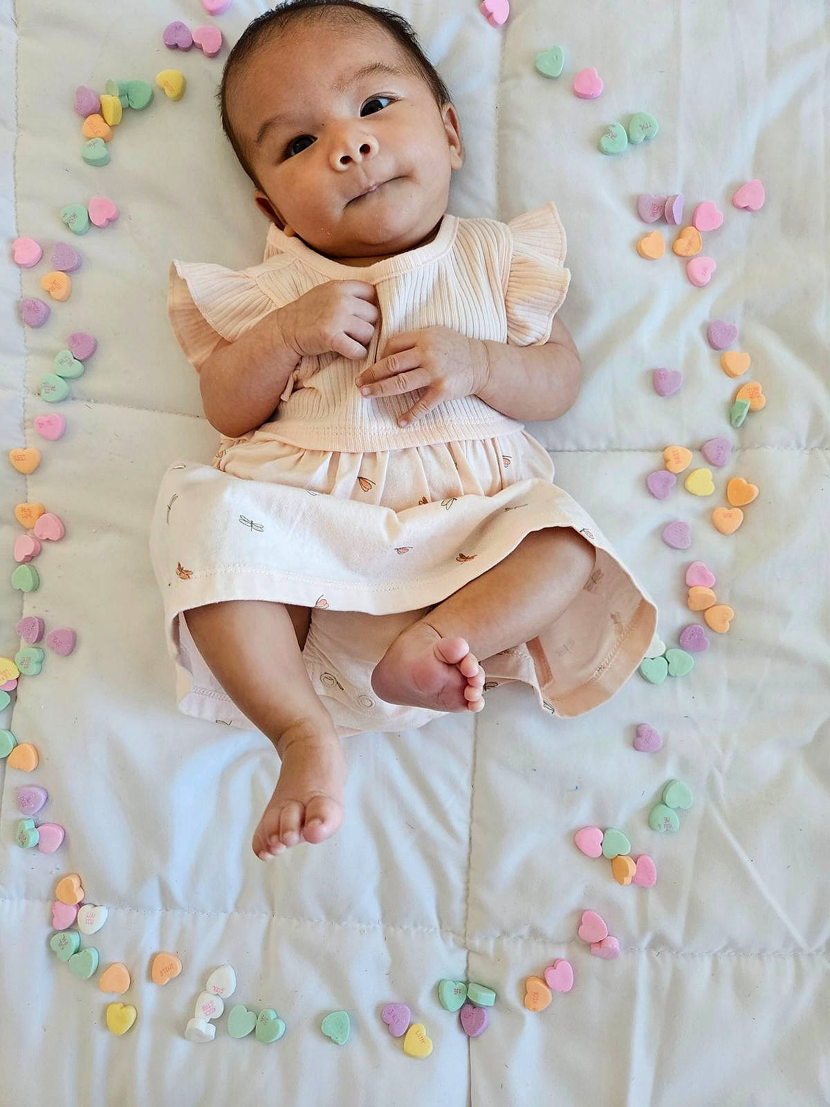 Elianna is registered to the contest to win money with this photo: baby, baby_products, baby_toddler_clothing, cheek, child, dress, fashion_accessory, happy, linens, magenta, pattern, peach, person, pink, product, sitting, skin, sleeve, textile, toddler