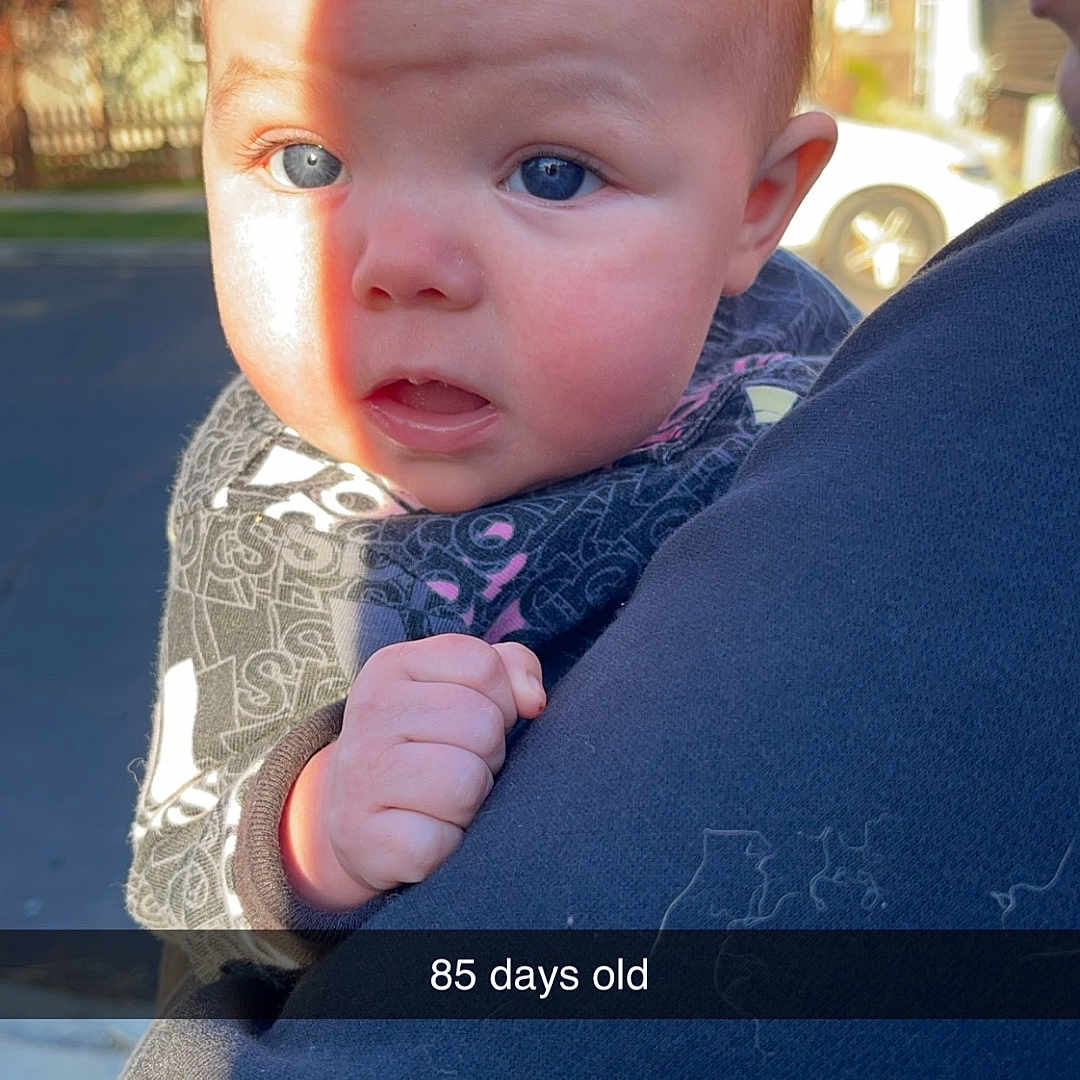 Shaelynn is registered to the contest to win money with this photo: baby, bodypart, city, clothing, coat, face, finger, hand, head, jacket, knitwear, pants, person, photography, portrait, road, street, sweater, t_shirt, urban