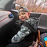 Hudson is registered to the contest to win money with this photo: backwards_cap, black_clothing, boy, camouflage, car, car_interior, child, handbag, happy, hoodie, outdoors, passenger, portrait, road_trip, seat, seated, smiling, trees, vehicle, window