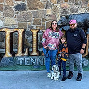 Ranger joined the competition — help win amazing prizes! backpack, bear_sculpture, casual_clothing, child, concrete, daylight, dog, family, hoodie, jeans, leash, outdoor, posing, sign, smiling, sneakers, stone_wall, sunglasses, tourist, urban