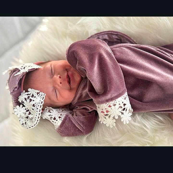Cambree is registered to the contest to win money with this photo: newborn, baby, sleeping, purple_outfit, lace, soft_texture, fluffy, white_background, infant, peaceful, cute, portrait, clothing, headwear, resting, tiny_hands, indoors, cozy, delicate, child