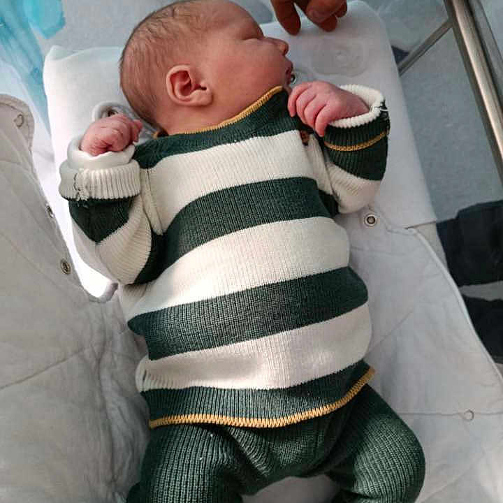 Thélio participe au concours pour gagner de l'argent avec cette photo : newborn, baby, infant, striped_clothing, knitwear, crib, hand, sleeping, cozy, soft_lighting, indoor, child, person, cute, small, resting, toddler, white, green, gentle
