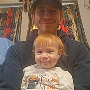 Selena is registered to the contest to win money with this photo: toddler, adult, smile, cap, sunglasses, indoor, curtains, patterned, happy, child, person, clothing, face, portrait, seated, home, casual, light, decor, fun