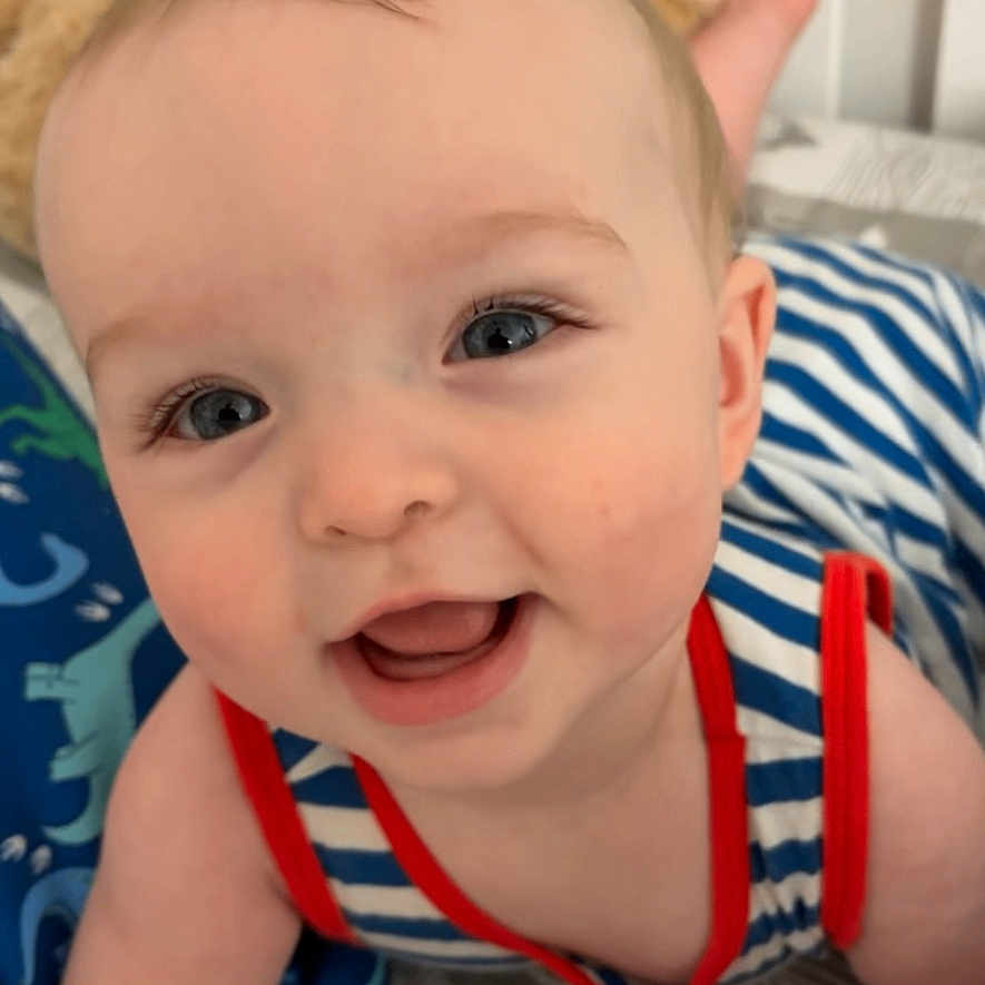 Jericho joined the competition — help win amazing prizes! baby, bed, blanket, blue_eyes, child, close_up, crawling, cute, face, happy, indoors, infant, person, plush_toy, portrait, skin, smiling, soft_lighting, striped_clothing, young_child