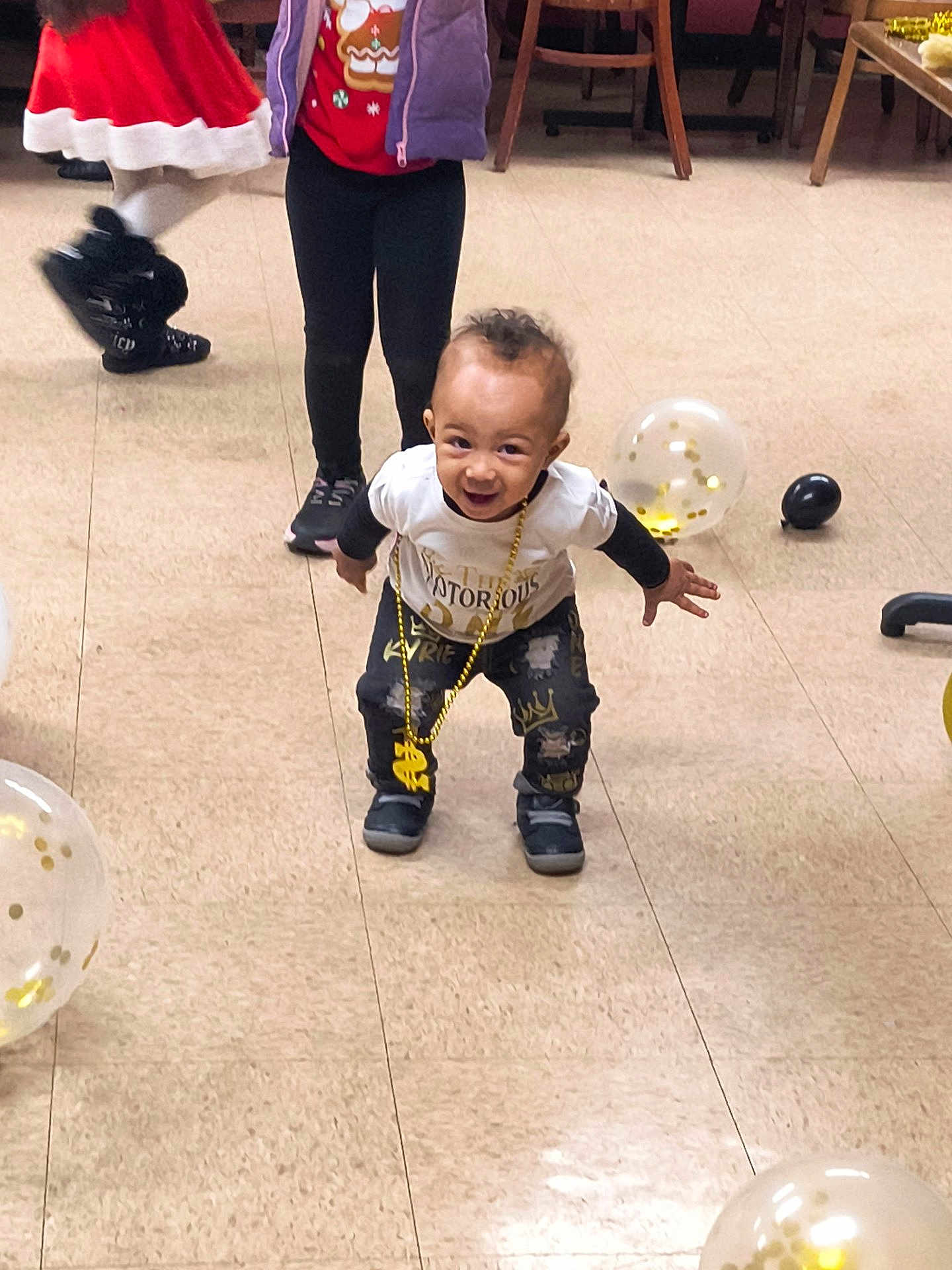 Kyrie joined the competition — help win amazing prizes! toddler, child, smile, playful, balloons, party, indoor, floor, clothing, gold_chain, sneakers, legs, people, celebration, festive, person, young_child, red_shirt, purple_jacket, black_pants