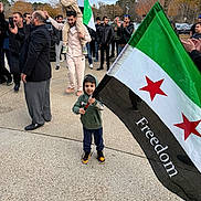 Sulaiman joined the competition — help win amazing prizes! children, child, crowd, outdoor, flag, freedom_flag, parade, gathering, people, family, boy, smiling, standing, shoulders, adult, autumn, trees, pavement, patriotic, community