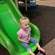 Sawyer joined the competition — help win amazing prizes! toddler, child, slide, playground, green_slide, barefoot, smiling, outdoor, sunlight, mulch, blue_pants, pink_shirt, short_sleeves, blonde_hair, happy, leisure, park, daytime, play, casual_clothing