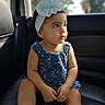 child, toddler, baby, portrait, sitting, car, car_interior, backseat, seat, bow, headband, dress, floral_pattern, face, eyes, looking_away, sunlight, indoors, vehicle, photography
