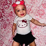 Meilani is registered to the contest to win money with this photo: baby, child, smiling, lying_down, onesie, headband, hello_kitty, pink_blanket, patterned_blanket, cute, happy, infant, clothing, face, person, small_child, indoor, skin, cheerful, wide_eyes