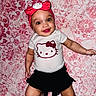 baby, child, smiling, lying_down, onesie, headband, hello_kitty, pink_blanket, patterned_blanket, cute, happy, infant, clothing, face, person, small_child, indoor, skin, cheerful, wide_eyes
