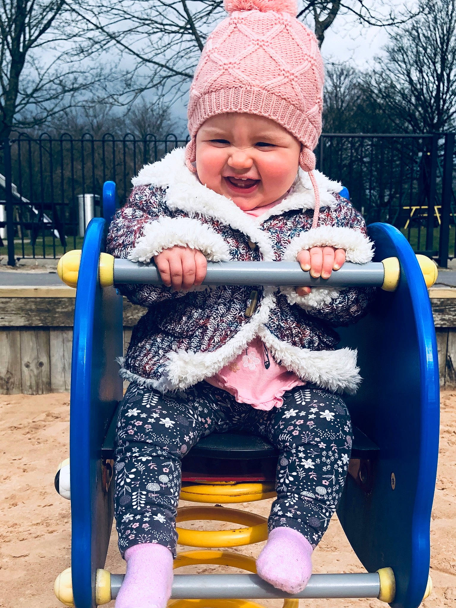 Bella is registered to the contest to win money with this photo: baby, child, fun, headwear, outdoor_play_equipment, person, pink, play, recreation, smile, swing, toddler, winter