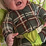baby, infant, smiling, plaid_clothing, onesie, baby_seat, child, happy, face, blue_eyes, playful, monkey_pattern, green, leaf_pattern, fabric, cute, indoor, person, seatbelt, young_child