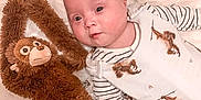 Killian a rejoint le concours — aidez-le/la à gagner de superbes lots ! animal_print, baby, book, child, childrens_book, cute, face, infant, lying_down, monkey, plush_toy, portrait, reading, smiling, soft_texture, striped_clothing, stuffed_animal, toddler, toy, white_background