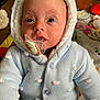 baby, blue_sweater, child, closeup, curious, cute, eyes, face, hooded_jacket, indoor, infant, knitted_clothing, newborn, pacifier, person, play_mat, polka_dots, portrait, soft_toys, warm_clothing