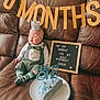 baby, banner, birthday, cake, celebration, child, clothing, couch, crown, decoration, food, half_birthday, happy, indoor, infant, party, portrait, signboard, sitting, sock