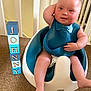 arm_up, baby, baby_seat, bib, blocks, blue, carpet, child, curly_hair, diaper, face, floor, home, indoor, letters, person, railing, sitting, smiling, white