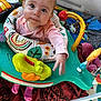 baby, child, infant, headband, pink_clothing, activity_center, toys, blanket, indoor, cute, play, expression, face, person, small_hands, floor, colorful, seat, looking_up, curious