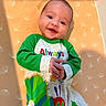 baby, smiling, onesie, caterpillar, infant, child, patterned_background, dandelion_print, happy, lying_down, colorful_clothing, cute, portrait, hands, face, playful, indoors, young_child, bright, cheerful