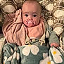 baby, pacifier, blanket, car_seat, patterned, pink, gray_clothing, child, indoor, cozy, cute, wide_eyes, soft_texture, infant, seated, fabric, toddler, wrapped, holding, portrait