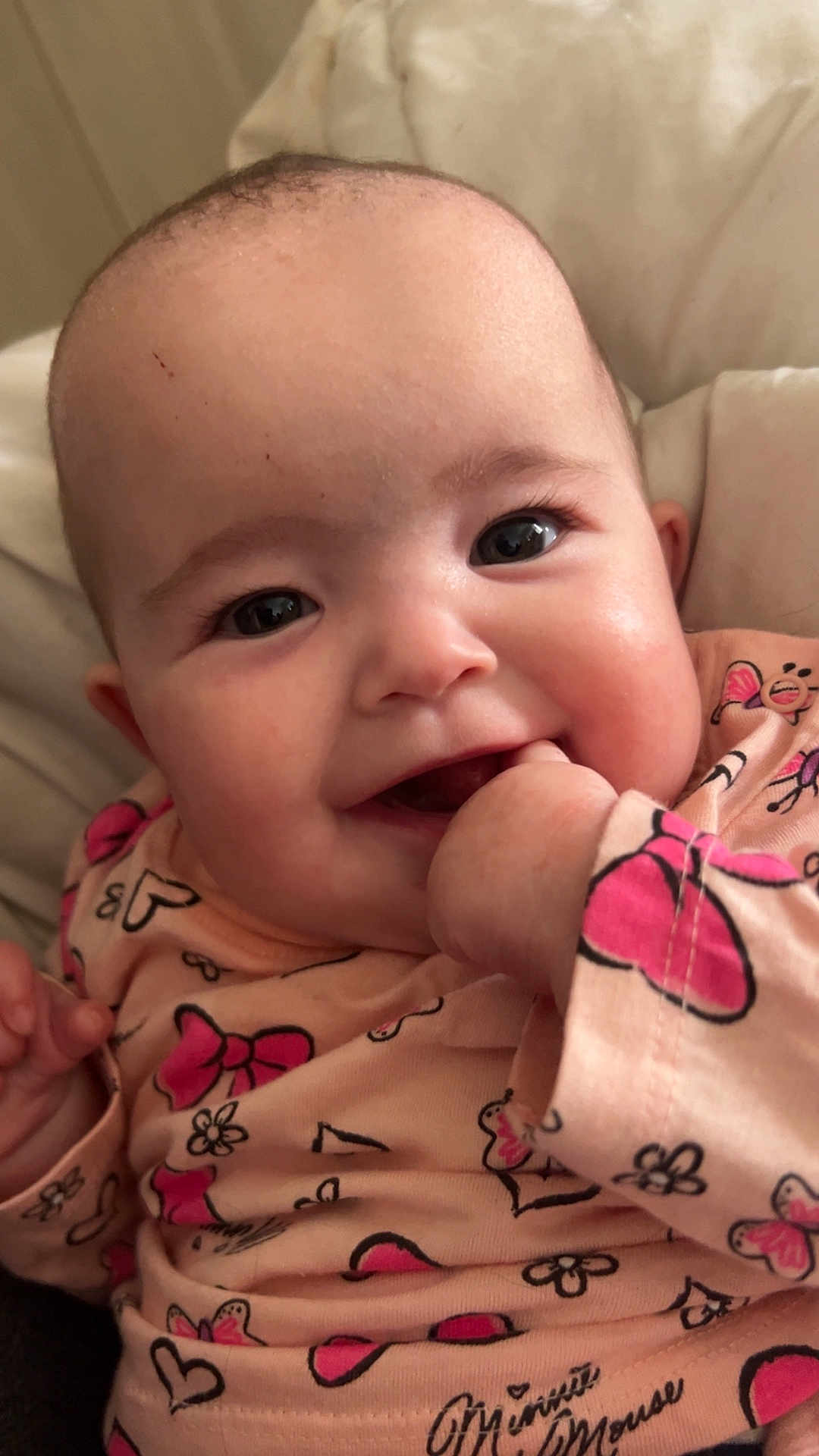 Ambre participe au concours pour gagner de l'argent avec cette photo : baby, smiling, close_up, face, hand, pink_clothing, butterfly_pattern, bow_pattern, chubby_cheeks, bright_eyes, infant, cute, happy, indoors, soft_light, child, person, apparel, sitting, playful