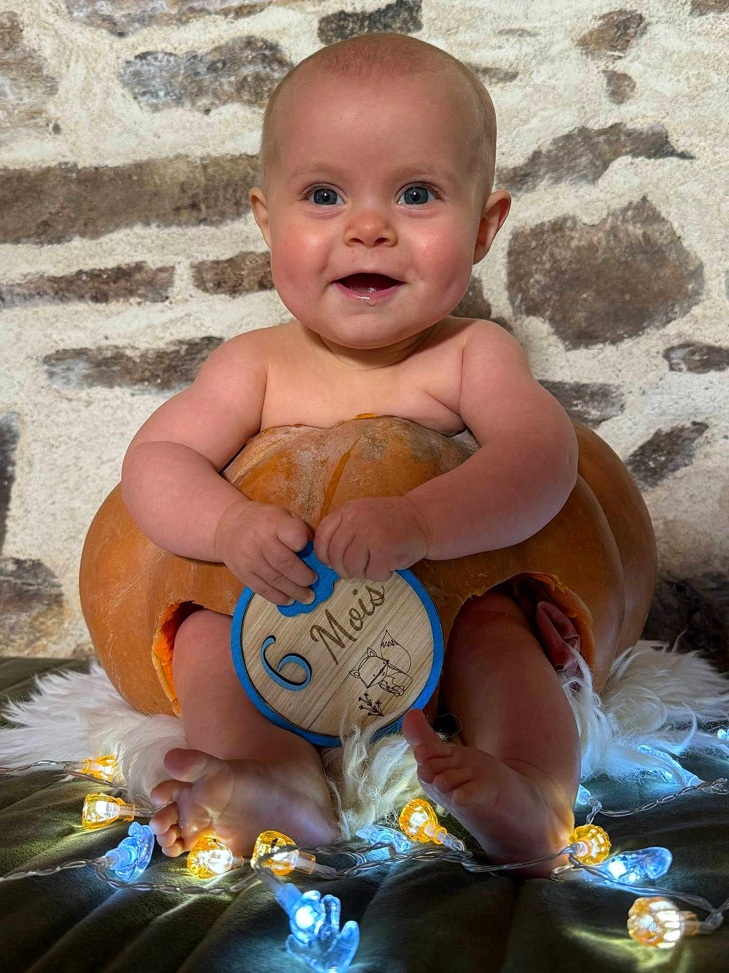 Elio a rejoint le concours — aidez-le/la à gagner de superbes lots ! baby, celebration, child, cute, decorative_lights, feet, happy, holding, hollowed_pumpkin, indoors, infant, lights, plush, portrait, pumpkin, sitting, six_months, smiling, stone_wall, wooden_plaque