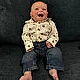 Parker is registered to the contest to win money with this photo: baby, infant, smiling, laughing, shirt, suspenders, jeans, barefoot, couch, sofa, home_interior, wood_paneling, cheeks, hands, toes, portrait, sitting, happy, eyes, furniture
