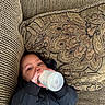 Kristian is registered to the contest to win money with this photo: baby, black_jacket, bottle, child, comfort, couch, cozy, cute, drinking, face, hand, indoor, infant, patterned_fabric, pillow, portrait, relaxing, resting, seated, young