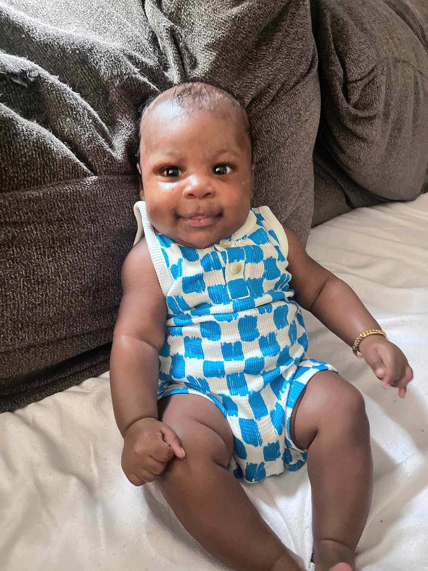 Kairo joined the competition — help win amazing prizes! baby, infant, child, romper, blue_and_white, checkered_pattern, bracelet, couch, brown, fabric, smile, sitting, indoors, cute, skin, person, young, happy, portrait, cozy