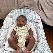 Kairo joined the competition — help win amazing prizes! baby, infant, child, onesie, animal_print, baby_seat, patterned_fabric, blanket, wooden_floor, indoors, cute, smiling, face, legs, feet, hand, relaxed, portrait, cozy, home